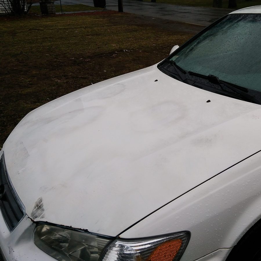 White car with dark spots on it from a bad paint job